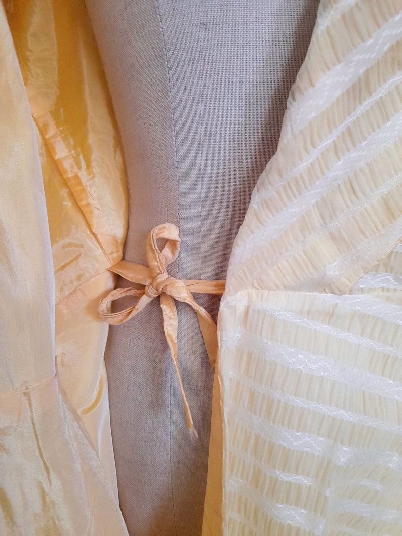 May include: A yellow sheer fabric with a white striped pattern. The fabric is tied with a yellow ribbon at the waist.
