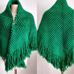 Puede incluir: Un chal de ganchillo verde con un diseño texturizado, abultado y ribeteado con flecos.