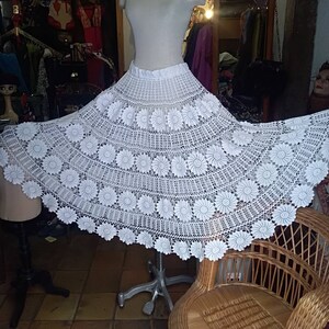 May include: White crochet skirt with a floral design. The skirt is full and flowing, and it is made of delicate crocheted lace.