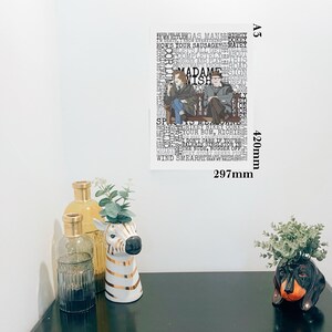 K&ouml;nnte beinhalten: Ein gerahmter A3-Druck (420 mm x 297 mm) mit zwei Figuren auf einer Bank, den Worten "MADAME WISH" und anderen Phrasen in einer Collage. Dekorative Elemente sind eine zebra-gestreifte Vase, Glasflaschen und ein Dackel-Pflanzgef&auml;&szlig;.
