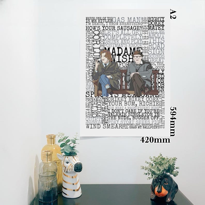 K&ouml;nnte beinhalten: Ein gerahmtes A2-Poster mit zwei M&auml;nnern auf einer Bank, umgeben von Text. Das Poster ist 420 mm breit und 594 mm hoch. Der Text enth&auml;lt S&auml;tze wie "Madame Wish" und "CRIKEY BIKEY CORK".