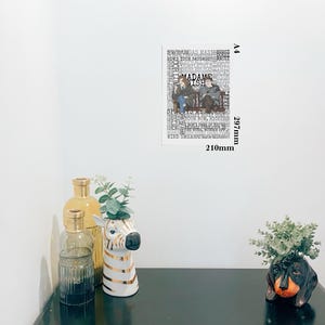 K&ouml;nnte beinhalten: A4-Poster mit einer Schwarz-Wei&szlig;-Illustration von zwei Personen und dem Text "MADAME WISH". Das Poster misst 210 mm x 297 mm. Dekorative Vasen, darunter ein zebra-f&ouml;rmiger Pflanzentopf, stehen auf einer schwarzen Oberfl&auml;che.