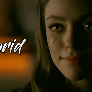 Może przedstawiać: Zbliżenie kobiety z jasnożółtymi oczami i ciemnymi smugami pod oczami. Słowo "Tribrid" jest napisane białym skryptem po lewej stronie obrazu. Tło jest rozmyte z ciepłymi tonami.