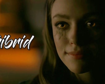 May include: A close-up of a woman with glowing yellow eyes and dark streaks under her eyes. The word "Tribrid" is written in white script on the left side of the image. The background is blurred with warm tones.