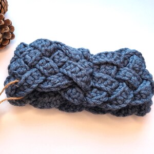 Peut inclure: Un bandeau tressé en crochet bleu. Le bandeau est fait d'un fil doux et texturé et présente un motif tissé. Le bandeau mesure environ 20 cm de large. Une étiquette jaune est attachée au bandeau.