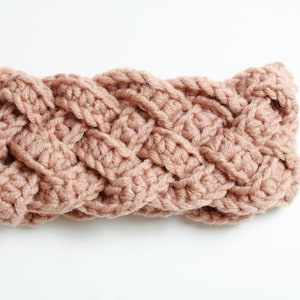 Peut inclure: Un bandeau tressé de couleur rose pâle. Le bandeau fait à la main est crocheté avec une grosse laine, créant un aspect texturé et tissé. Le bandeau est conçu pour être porté autour de la tête.