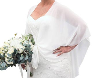 May include: A sheer white chiffon bolero wrap featuring a draped, open-front design that ties at the centre with a small, circular silver-toned clasp. The lightweight fabric creates soft, flowing sleeves that extend over the shoulders and arms.