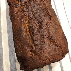 May include: A loaf of freshly baked banana bread, with a golden brown crust and a slightly cracked surface.