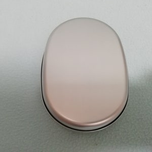 Puede incluir: Una fiambrera ovalada de color plateado con una superficie lisa y brillante.