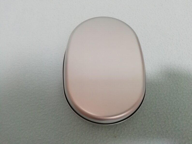 Puede incluir: Una fiambrera ovalada de color plateado con una superficie lisa y brillante.