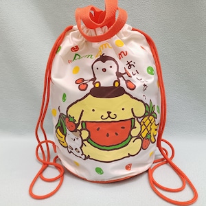 Puede incluir: Bolsa con cordón blanca con una ilustración de dibujos animados de un personaje amarillo con forma de perro sosteniendo una rodaja de sandía. La bolsa tiene cordones rojos y un asa a juego. El diseño incluye frutas y texto japonés.