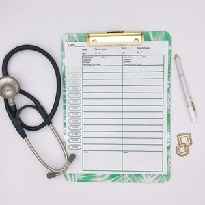 May include: A white clipboard with a green tropical leaf pattern, labeled "Date", "Patient Name", "Time", "Code Status", "Diagnosis", "Allergies", "Attending Care Team", and "Notes". A stethoscope and a white pen are on a white surface next to the clipboard.