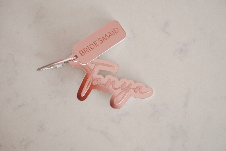 Puede incluir: Llavero de oro rosa con la palabra "BRIDESMAID" y el nombre "Tanya" escrito en cursiva.