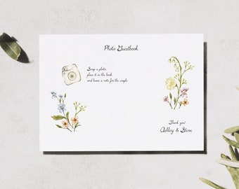 Puede incluir: Una tarjeta blanca con el texto "Photo Guestbook" e instrucciones para "Tomar una foto, colocarla en el libro y dejar una nota para la pareja". La tarjeta también tiene una pequeña ilustración de una cámara y flores. El texto "Gracias, Ashley & Steve" está en la parte inferior de la tarjeta.