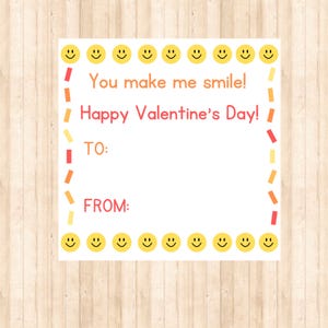May include: A white Valentine's Day card featuring a border of yellow smiley faces. The card includes the text "You make me smile! Happy Valentine's Day!" and spaces for "TO:" and "FROM:" in red.