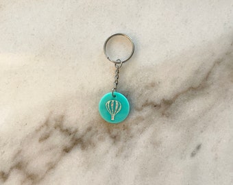 Keychain with the word serene stamped on a washer with hot air balloon charm and green crystal.