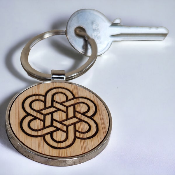 Lucky infinite knot key ring in wood and metal. The endless knot symbol of Tibetan Buddhism engraved on bamboo. Spirituality.