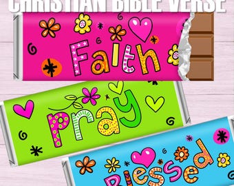May include: Three colorful chocolate bar wrappers with the words "Faith", "Pray", and "Blessed" in a whimsical font. The wrappers are pink, green, and blue, decorated with hearts, flowers, and stars. The text "Christian Bible Verse" is at the top.