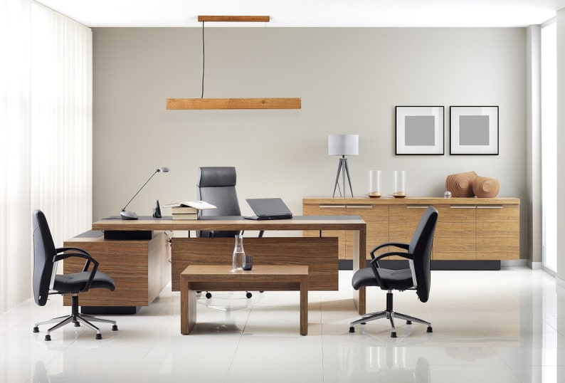 May include: A modern office space with a large wooden desk, two black office chairs, a wooden side table, and a wooden cabinet. The desk has a black leather chair, a laptop, and a lamp. The room has a wooden ceiling light and two framed pictures on the wall.