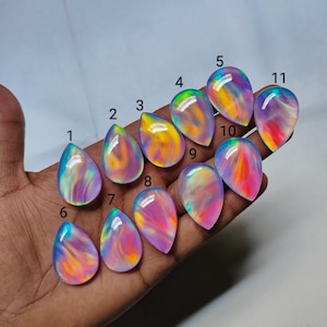 May include: Eleven iridescent teardrop-shaped cabochons in various shades of pink, purple, and yellow with a rainbow sheen. The cabochons are numbered 1 through 11.