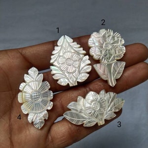 May include: Four white mother of pearl flower carvings with intricate details. The carvings are numbered 1 through 4.