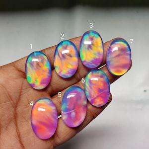 May include: Seven oval-shaped opals with swirling patterns of color. The opals display a range of hues, including pink, purple, blue, yellow, and green. Each stone is polished and has a smooth, glossy surface, perfect for jewelry making.