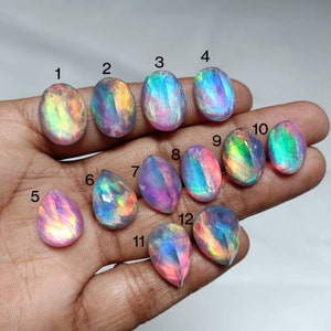 Op de afbeelding: Twaalf regenboogkleurige, iriserende ovale en druppelvormige edelstenen. De edelstenen zijn genummerd van 1 tot en met 12.