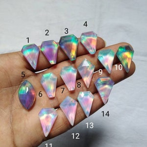 Könnte beinhalten: Sortiment von 14 regenbogenfarbenen Edelstein-Cabochons in verschiedenen Formen und Größen. Die Cabochons sind eine Mischung aus hellrosa, lila und blauen Farben mit einem Regenbogen-Schimmer.