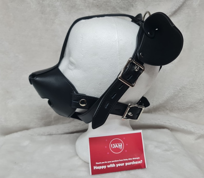 May include: Black leather dog muzzle with a strap and a black leather ear piece. The muzzle is on a white mannequin head. The text on the card reads "Happy with your purchase?"