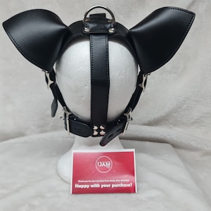 May include: Black leather dog mask with large ears and a silver buckle. The mask is on a white mannequin head. The text on the card reads "Happy with your purchase?"