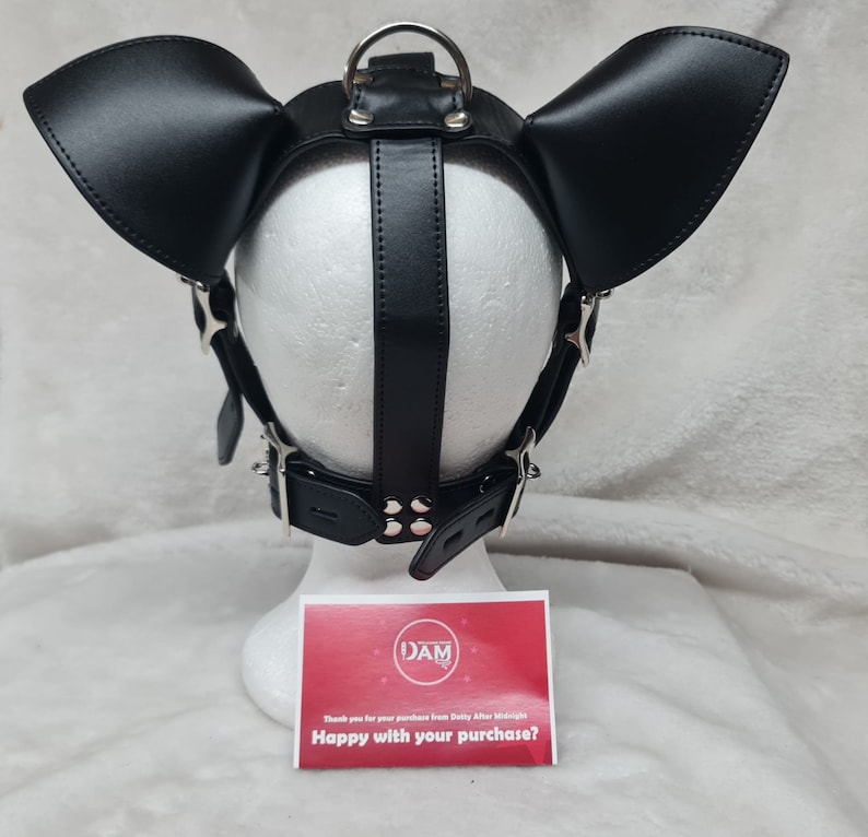 May include: Black leather dog mask with large ears and a silver buckle. The mask is on a white mannequin head. The text on the card reads "Happy with your purchase?"