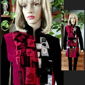Può includere: Giacca nera dal design unico. Presenta un patchwork di forme geometriche e numeri rossi, neri e bianchi. La giacca ha un collo alto e due grandi bottoni. Presentata su un manichino.