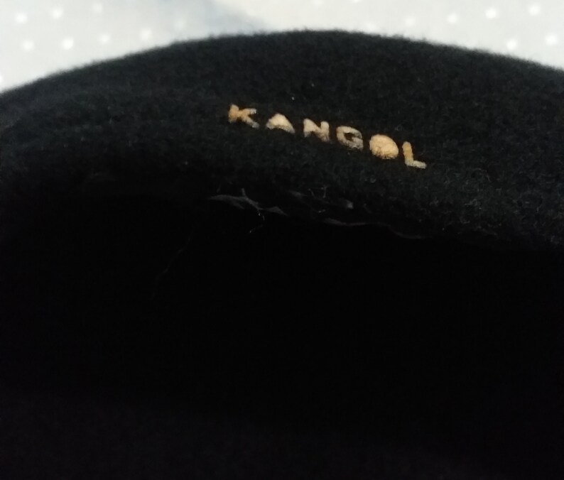 May include: Black wool beret with a gold "Kangol" logo.