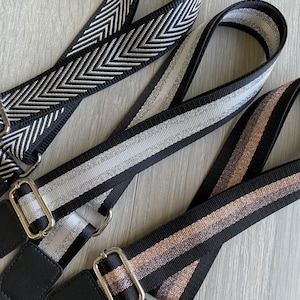 Peut inclure: Trois sangles en tissu rayées noir et blanc avec des accents argentés et dorés. Les sangles sont munies de ferrures métalliques et conviennent aux sacs ou aux sacs à main.