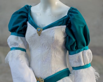 May include: A white and teal wedding dress with a fitted bodice, a full skirt, and long sleeves. The dress features a teal sash with a gold buckle and a white lace trim.