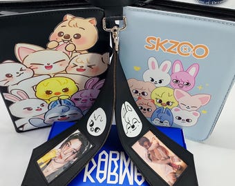 May include: Black leather choker with a silver clasp and two black pendants featuring photos and cartoon faces. The pendants are connected to a blue box. Two zippered pouches with cartoon character designs are in the background.