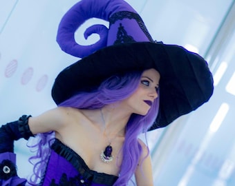 May include: A purple and black witch hat with a curled top, paired with a purple corset featuring black lace trim, black arm warmers with ruffled edges, and a silver pendant necklace with a dark purple stone, worn with long purple hair.