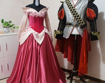 May include: A floor-length gown with a deep red satin skirt, a velvet bodice, and off-the-shoulder pale pink sleeves with floral embroidery, paired with a silver quilted doublet featuring black sleeves, red accents, gold trim, and a belt with a buckle.
