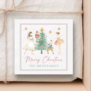 May include: A square Christmas gift tag with a watercolor illustration of a Christmas tree, nutcracker, and ballerinas. The tag reads "Merry Christmas" and "The Smith Family" in a red and green border. The gift is wrapped in white paper and tied with twine.