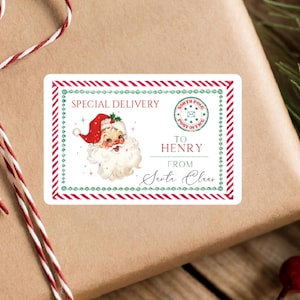 May include: A rectangular gift label featuring a red and green striped border, a vintage illustration of Santa Claus, and the text Special Delivery, North Pole Post Office, To Henry, and From Santa Claus, printed on a white background.