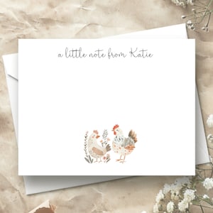 May include: A white card with the text "a little note from Katie" at the top. The bottom of the card features a watercolor illustration of two chickens in a field of flowers.