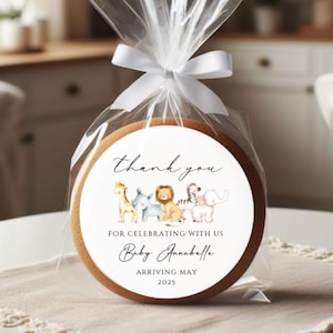 May include: A white round sticker with a thank you message and a group of safari animals. The text reads "Thank you for celebrating with us Baby Annabelle Arriving May 2025".