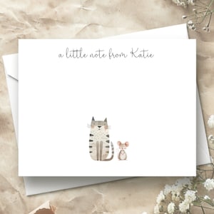 May include: A white card with the text "a little note from Katie" at the top. A gray and white cat and a brown mouse are illustrated at the bottom of the card.