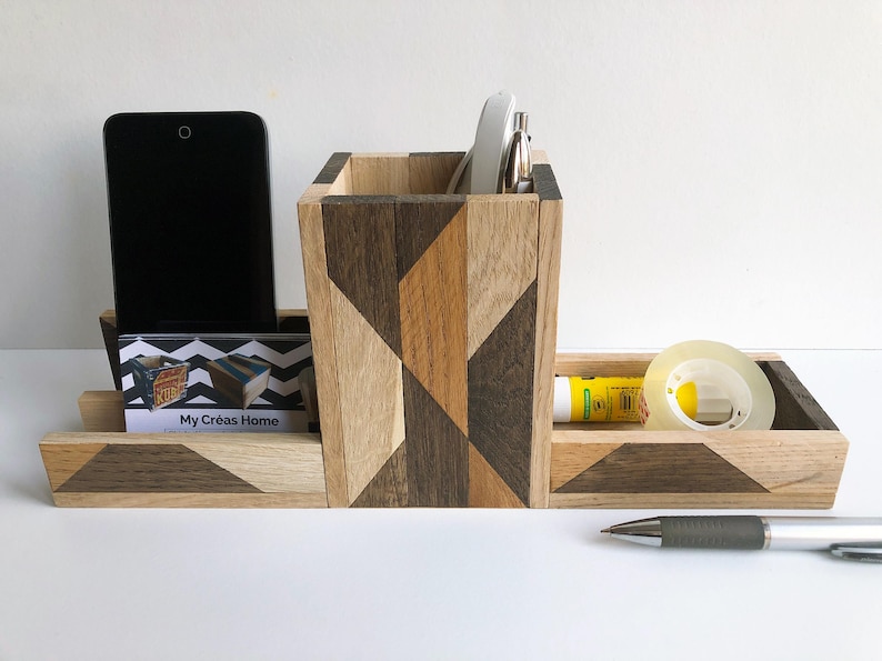 May include: A wooden desk organizer with a geometric pattern in shades of brown and beige. It has compartments for a phone, business cards, pens, and other office supplies. The organizer is labeled "My Creas Home".