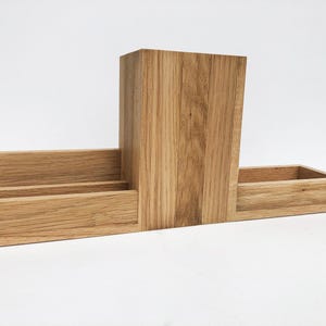 May include: A wooden desk organizer with three compartments. The organizer is made of light brown wood and has a natural finish.