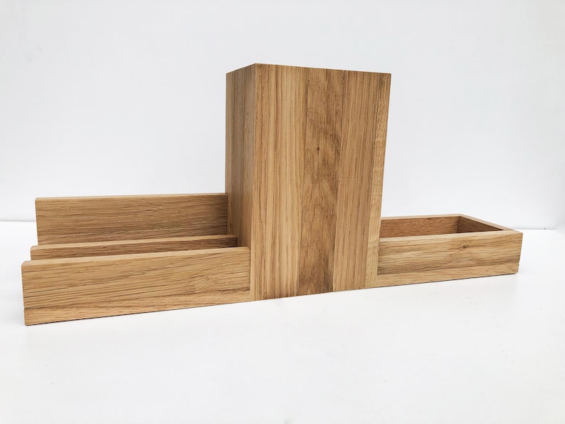 May include: A wooden desk organizer with three compartments. The organizer is made of light brown wood and has a natural finish.