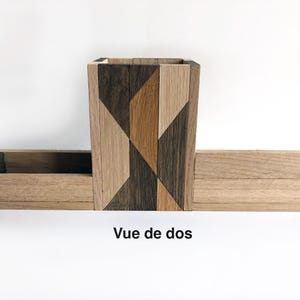 May include: A wooden organizer with a geometric pattern on the front. The organizer has a small box on top and a larger box on the bottom. The text "Vue de dos" is written below the organizer.