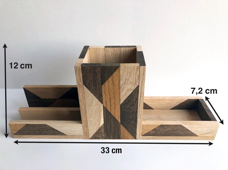 May include: A wooden desk organizer with geometric patterns in shades of brown, black, and beige. The organizer has a central compartment measuring 12 inches tall and two smaller compartments measuring 7.2 inches wide. The overall length of the organizer is 33 inches.