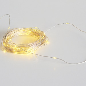 May include: A coiled string of warm white LED fairy lights on a silver wire. The lights are clustered together in a spiral, with some strands extending outward. The lights are on, emitting a soft glow, and are suitable for decorative purposes.