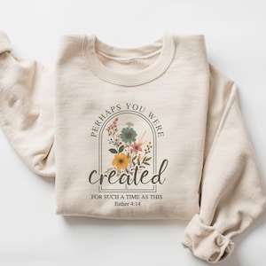 May include: A beige sweatshirt with a floral design and the text "Perhaps you were created for such a time as this Esther 4:14".
